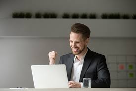 успешный мужчина улыбается и смотрит в ноутбук